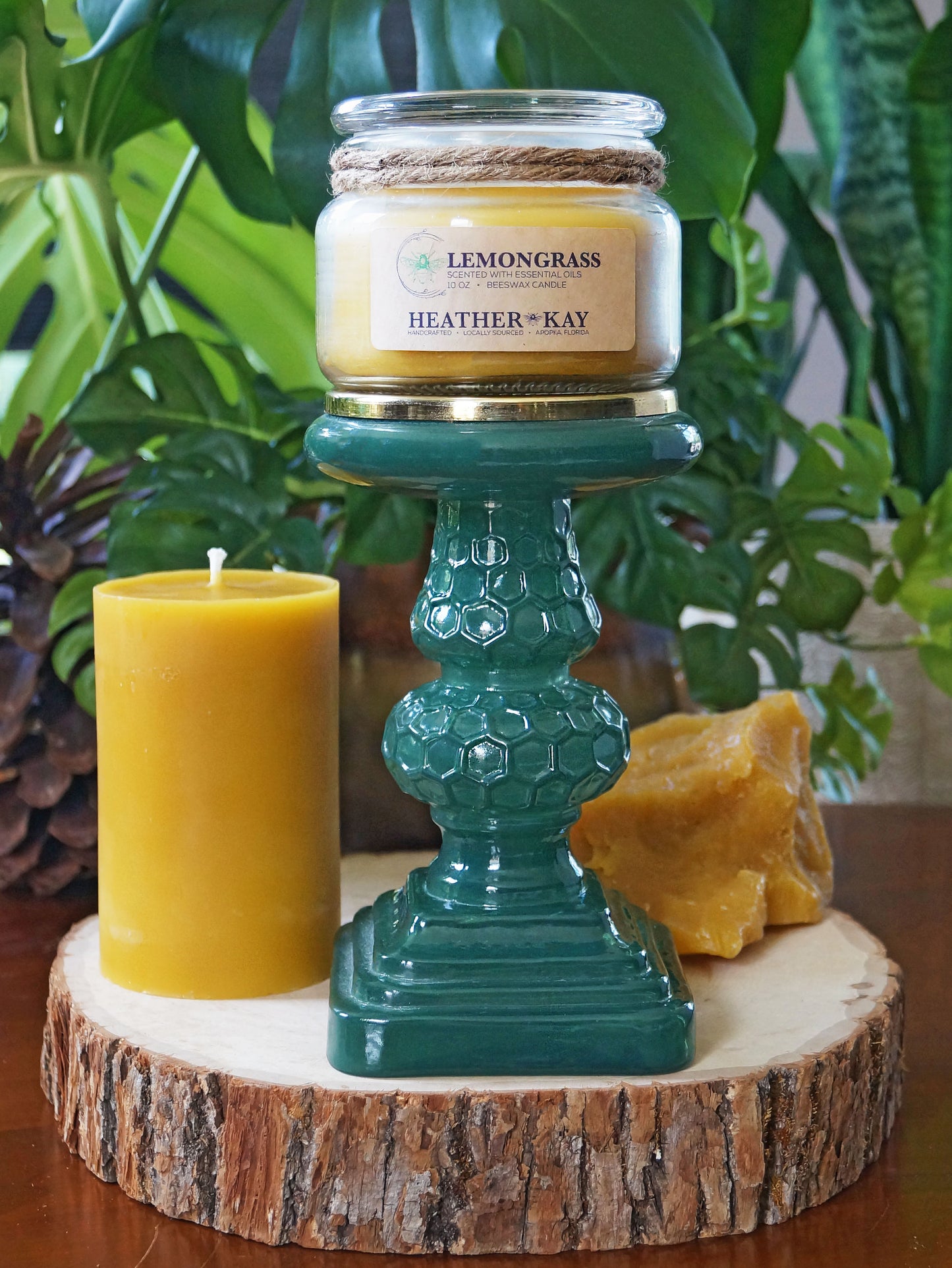 lemongrass essential oil beeswax candle in glass jar with natural cotton wick sitting on a stand with beeswax candle in the background